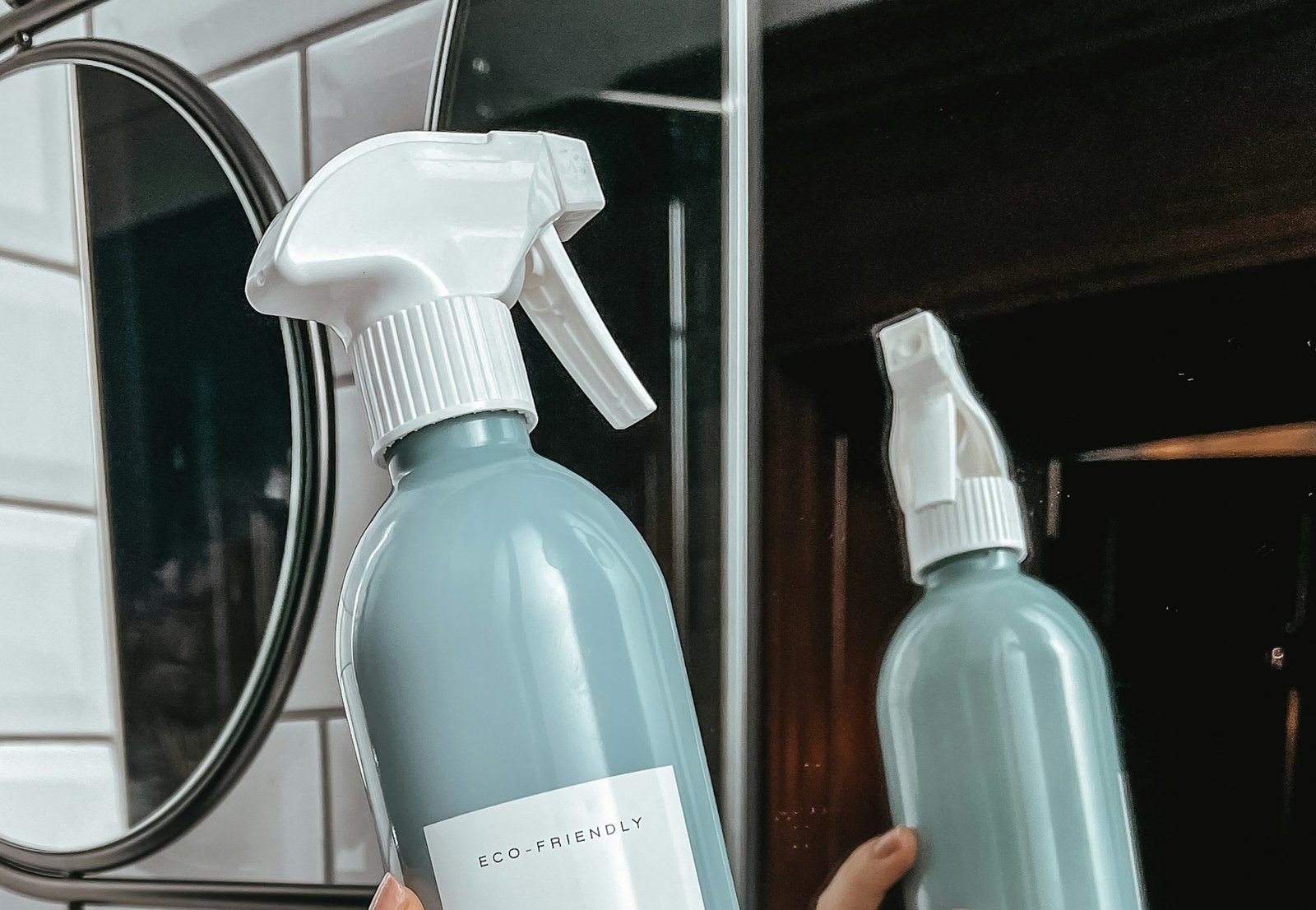 Hand reinigt einen Badezimmerspiegel mit einem Tuch